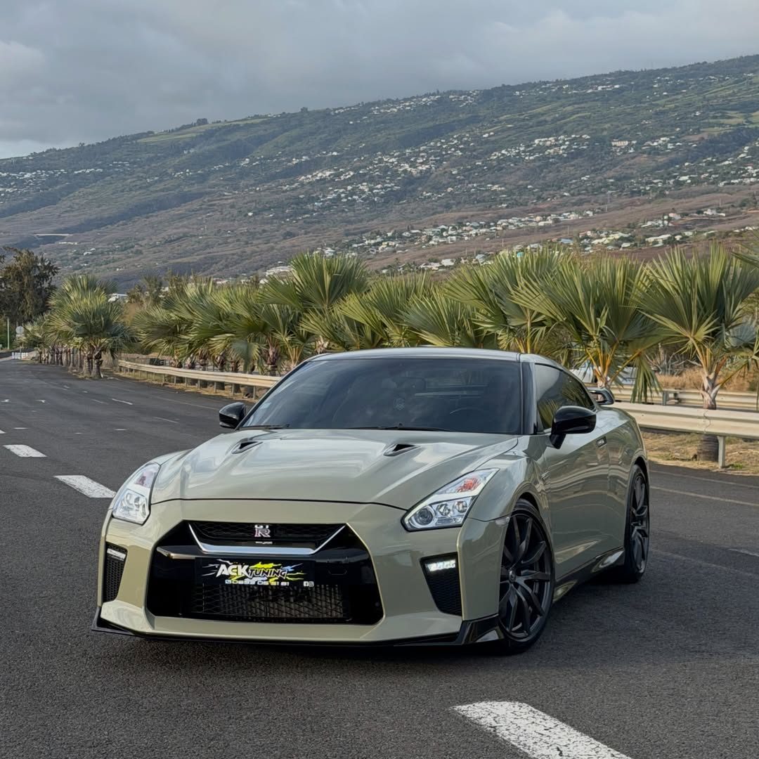 Nissan GTR recouverte d'un film kaki HEXIS HX One sur une route de l'Ouest, palmiers et mi-pentes de Saint-Leu en fond