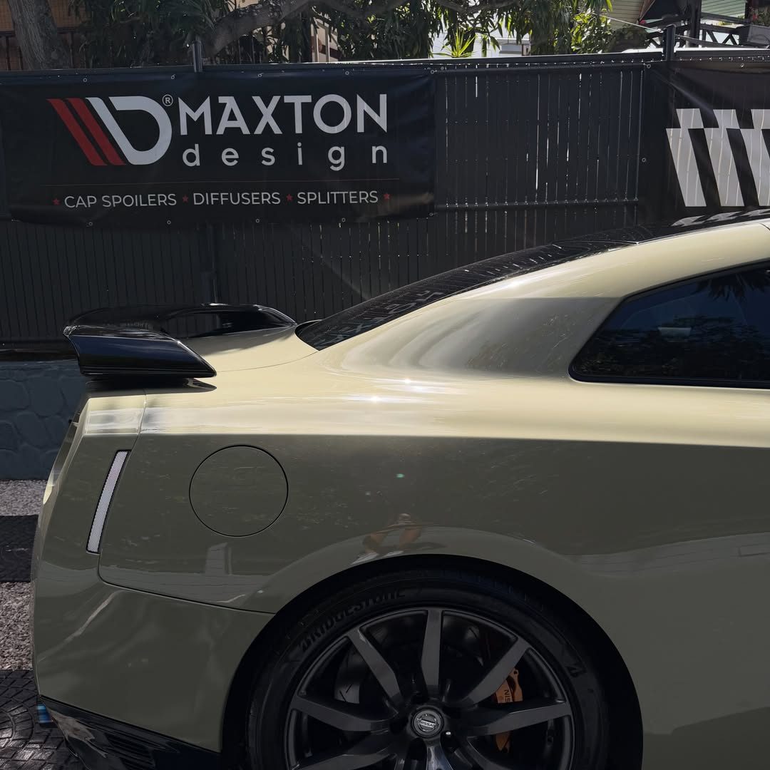 Arrière d'une Nissan GTR kaki devant la bâche Maxton Design de l'atelier